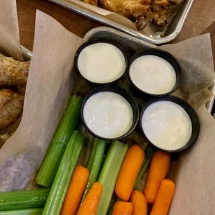 a tray of carrots, celery, and dips