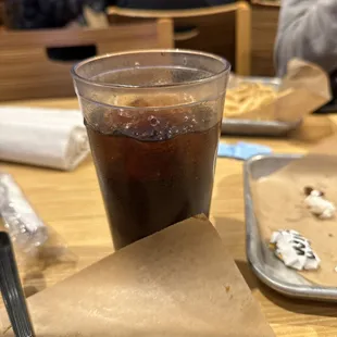 a glass of soda and a half eaten sandwich