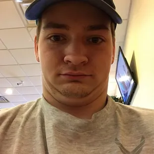 a man in a gray shirt and a green hat