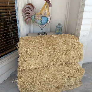 a rooster and hay bale