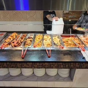 a variety of food being served at a buffet