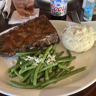 a plate of meat, mashed potatoes, and green beans