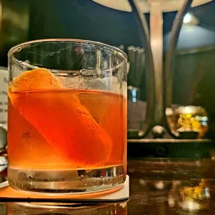 a drink in a glass with an orange garnish