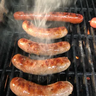 hot dogs cooking on a grill