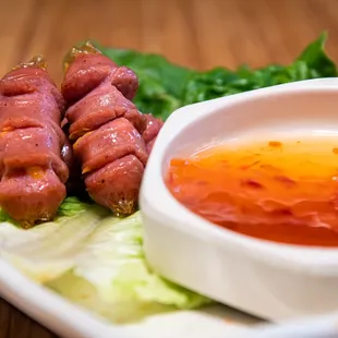 a plate of meat wrapped in lettuce and dipping sauce