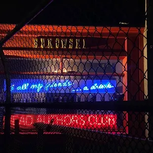a neon sign on a chain link fence