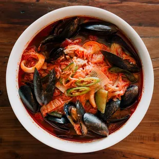 a bowl of stew with musselling and seafood