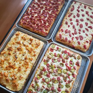 four pans of different pizzas