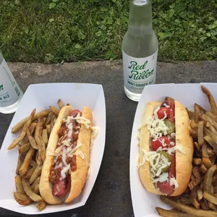 Chili cheese dog and a dog with cheese, pickle and tomato