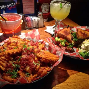Basket of loaded waffle fries, twisted BLT, Voodoo rum bucket and House Margarita.
