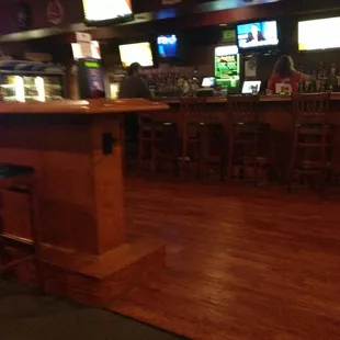 a bar with stools and televisions