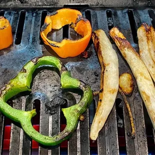 peppers and other vegetables cooking on a grill