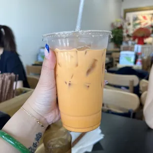 a hand holding a plastic cup of iced tea
