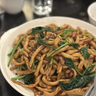 a plate of noodles with spinach and mushrooms