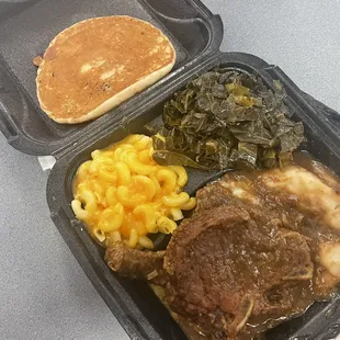 The smothered pork chop dinner with 2 Smothered Pork Chops, mashed potatoes, mac and cheese, and collard greens, and corn bread.