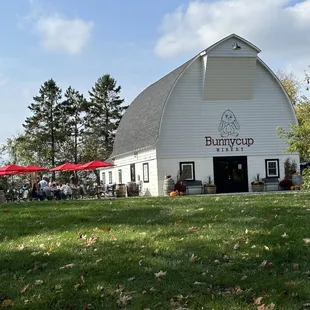 a white barn with red umbrellas