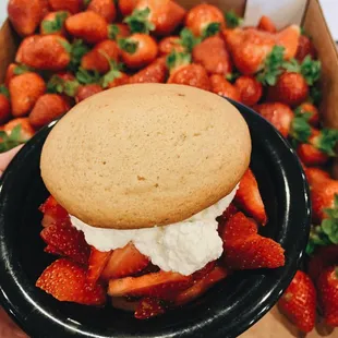 a person holding a plate of strawberries and a cookie