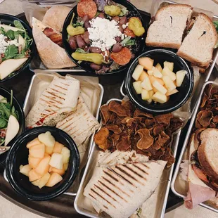 a platter of sandwiches, salads, and fruit
