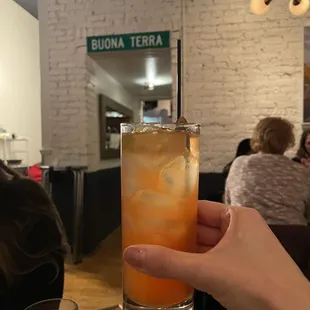 a hand holding a tall glass of iced tea