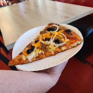 Slice of pizza  with onion olive  and a little mild hot sauce