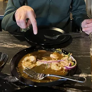 a man sitting at a table with a bowl of soup and a glass of beer