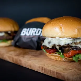 three burgers on a cutting board