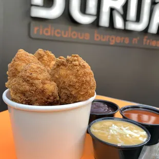 a bowl of fried chicken with dipping sauces