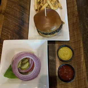 Hamburger and fries with fixings on the side.