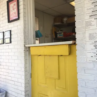 a yellow door in a white brick building