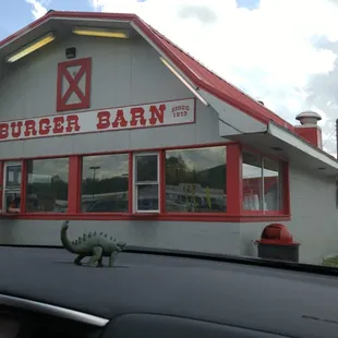a dinosaur in front of a burger barn