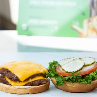 two burgers with cheese, tomato, and lettuce