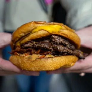 a person holding a hamburger in their hands