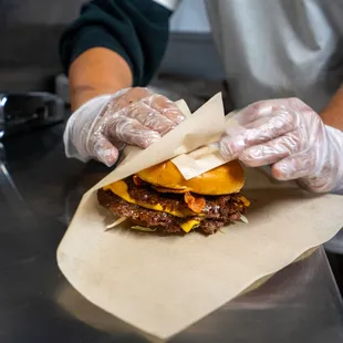 a person in a kitchen preparing a burger