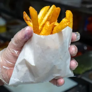 a hand holding a bag of fries