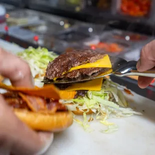 a person cutting a hamburger with a knife