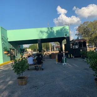people sitting at tables in front of a green building