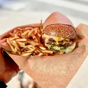 a hand holding a basket of fries
