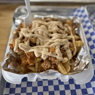 a tray of fries with a fork sticking out of it
