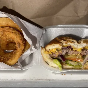 Half eaten cheeseburger and onion rings.
