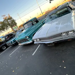 a row of classic cars parked in a parking lot