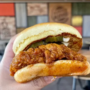a hand holding a chili chicken sandwich