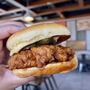 a hand holding a fried chicken sandwich