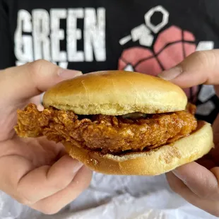a hand holding a chicken sandwich