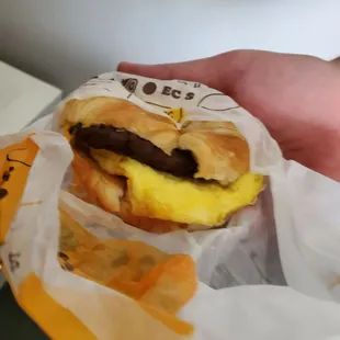 a hand holding a sandwich wrapped in paper