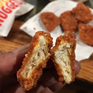 a hand holding a half eaten chicken nuggies