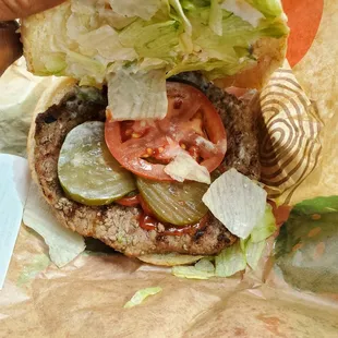 a hamburger with lettuce, tomatoes, and pickles