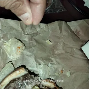 a hand reaching for a piece of cheeseburger