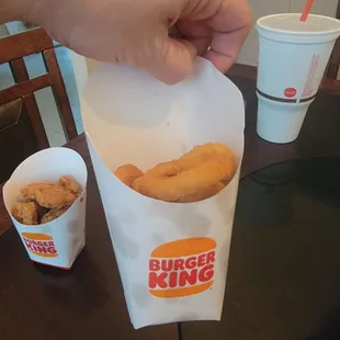 a hand holding a bag of fried food