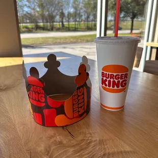 a cup and a paper crown on a table