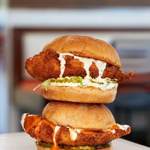 two fried chicken sandwiches stacked on top of each other